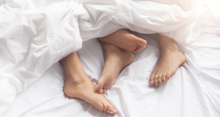 Bett mit Füßen von Mann und Frau