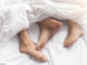Bett mit Füßen von Mann und Frau