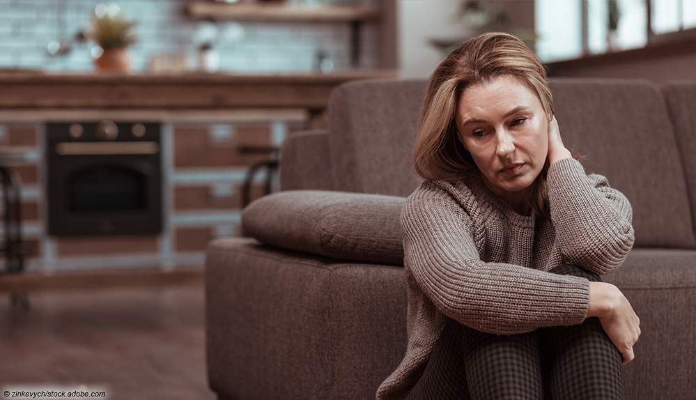 Frau sitzt traurig vor Couch