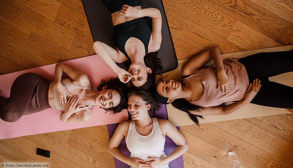 Frauen liegend lachend auf Yogamatten