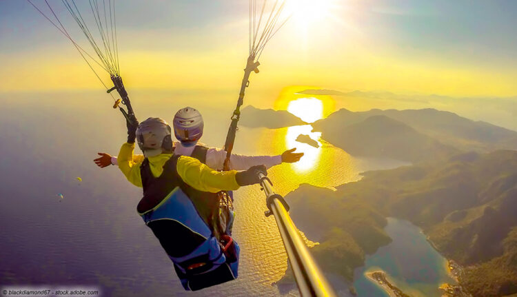 Paraglider fliegen zur Sonne über dem Meer