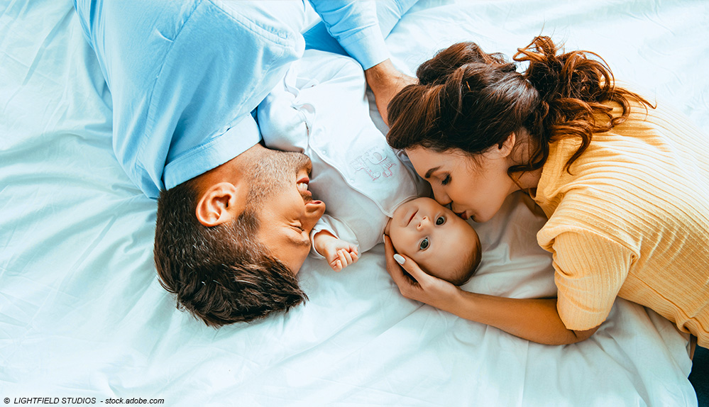 Vater und Mutter im Bett mit Baby