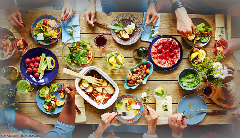 reich gedeckte Dinnertafel mit Gemüse und Freunden, die gemeinsam essen