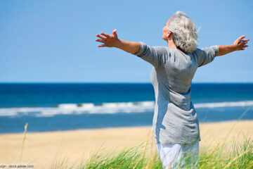 stehende Frau am Sandstrand am Meer