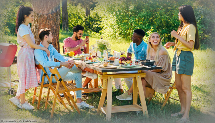 Freunde sitzen im Garten an einem reich gedeckten Tisch