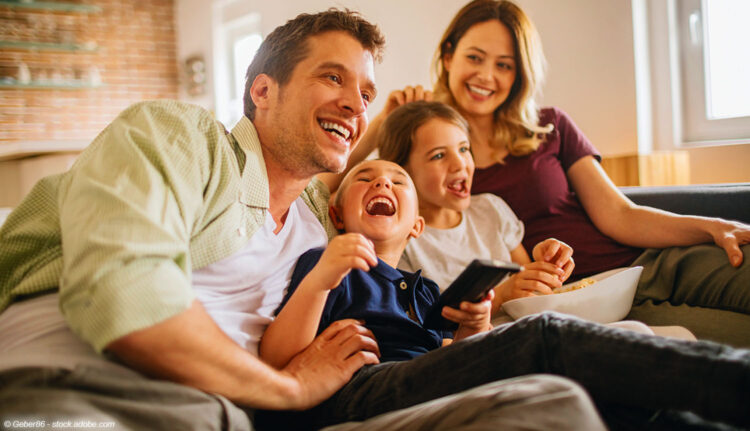 lachende Familie auf Couch vor Fernseher