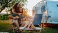 Paar vor Camper mit Gitarre und Lagerfeuer